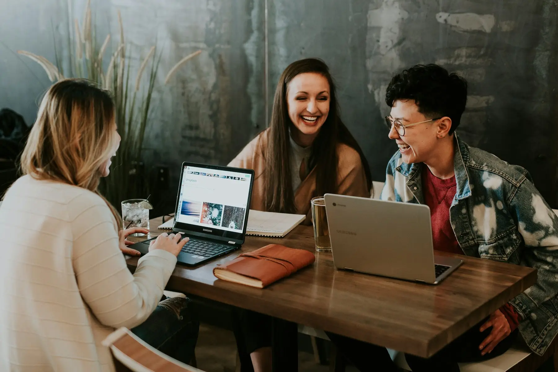 Three people talking around a table with laptops