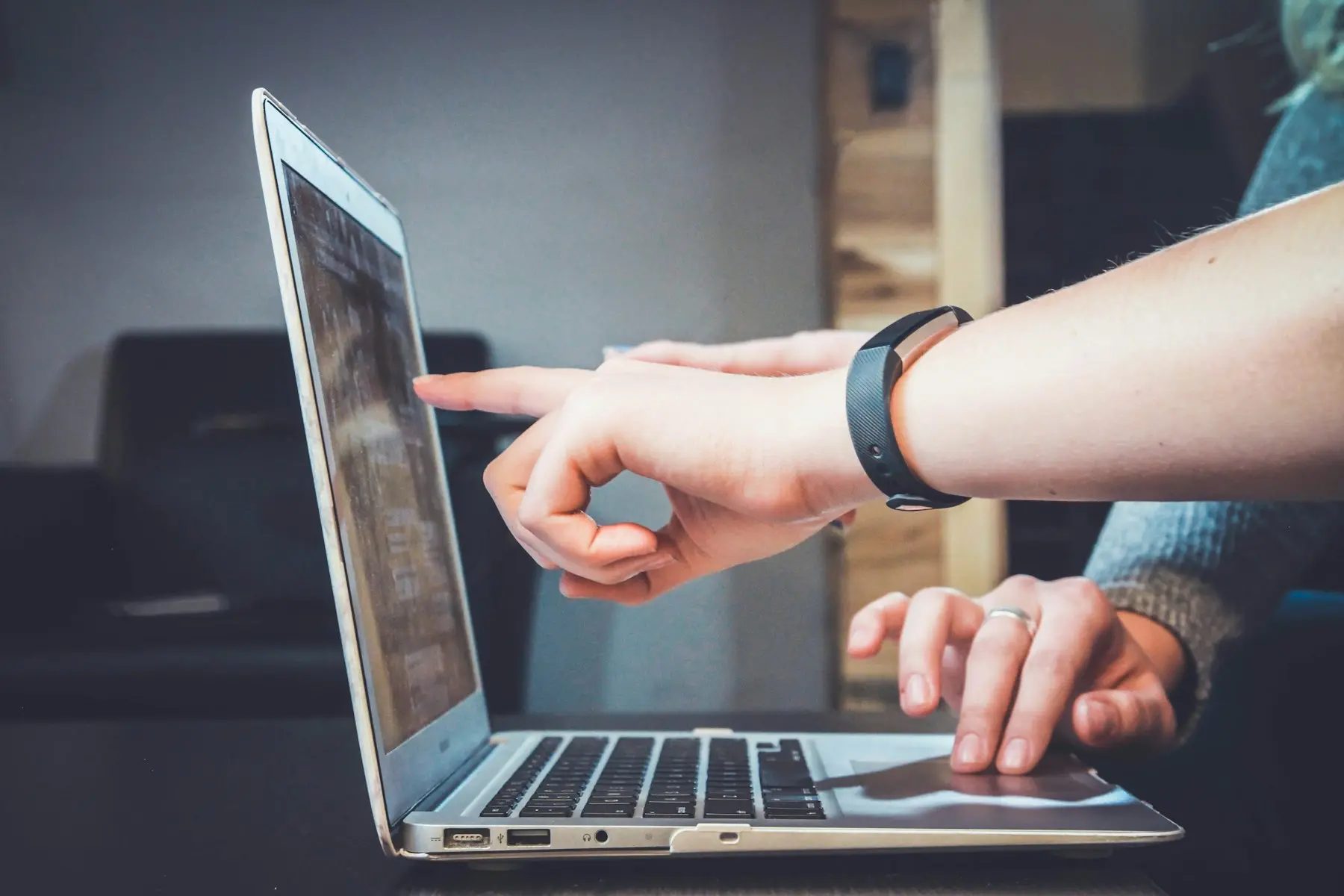 Two people at a laptop, one pointing to something on the screen